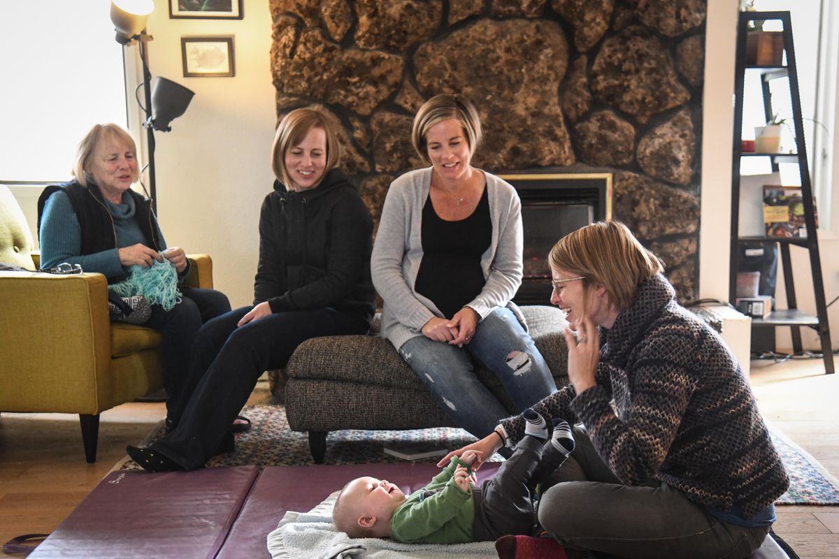 Erika Ellis plays with her son, Arlo, on the floor as her mother Jeannie Wagnor, left, and sisters Krista Cumberland and Andrea Ortiz watch during a visit on Feb. 17. Krista was the surrogate mother for Arlo, and Andrea was the surrogate with the yet-to-be-born Ada in this photo. Ada arrived on Feb. 29. (Dan Pelle / The Spokesman-Review)