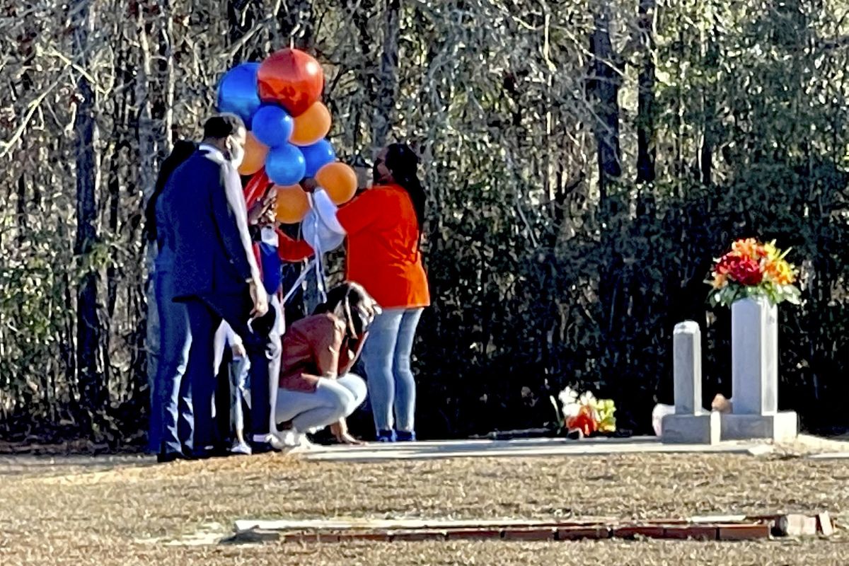 In this Feb. 23, 2021 photo, Wanda Cooper-Jones kneels before the grave of her son, Ahmaud Arbery, at the New Springfield Baptist Church in Waynesboro, Ga., to mark the one year anniversary of Ahmaud Arbery