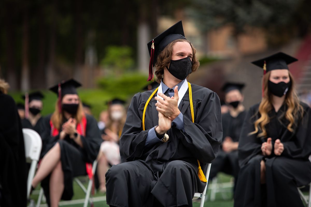 Students listen during a graduation ceremony for the undergraduate class of 2021 on Sunday, May 23, 2021 at the Whitworth Pine Bowl in Spokane, Wash. The outdoor ceremony was socially distanced with guests spread among the stands and seated on the field behind the graduates, everyone had to wear masks except to receive a diploma and no handshakes were permitted on stage.  (Libby Kamrowski/ THE SPOKESMAN-REVIEW)