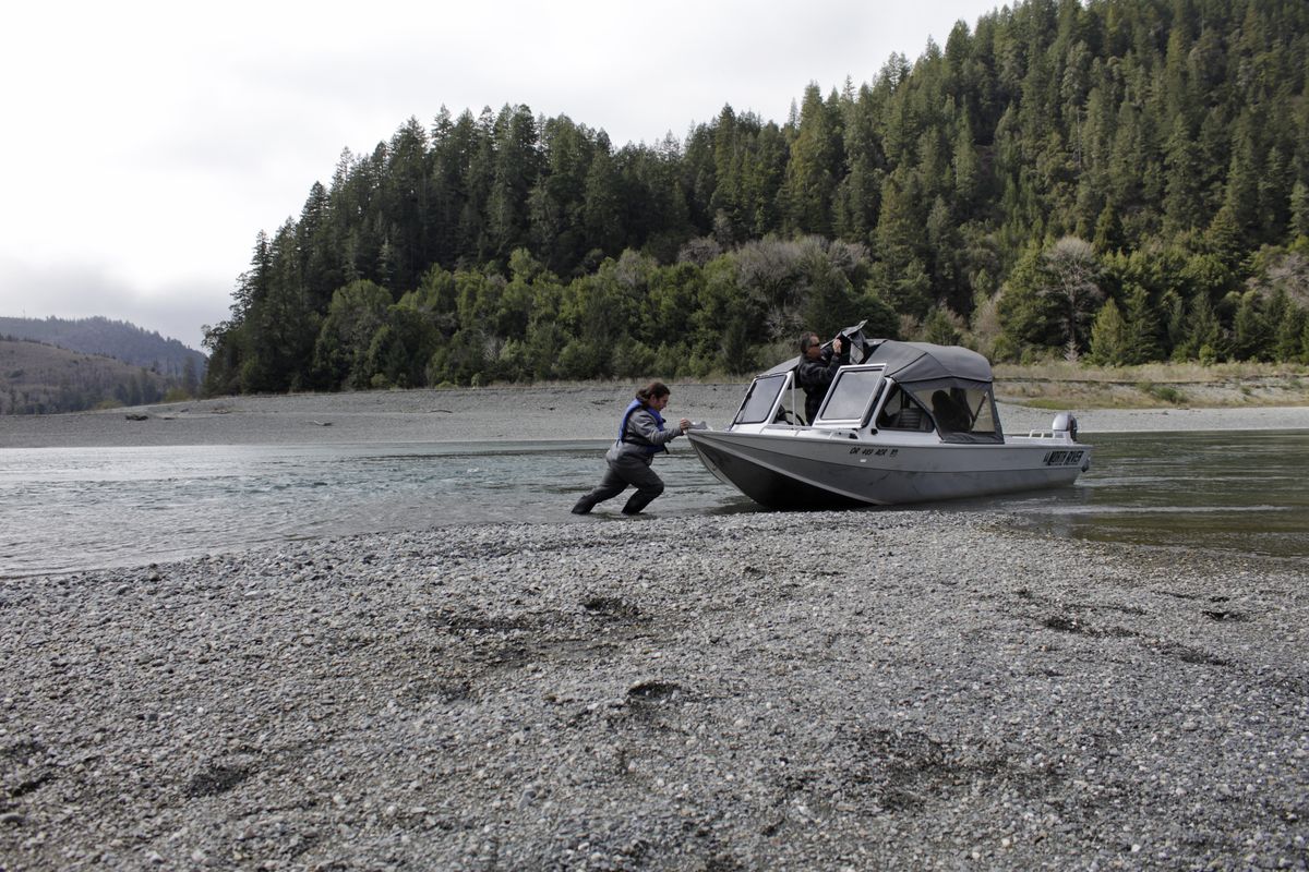 Hunter Maltz, a fish technician for the Yurok tribe, pushes a jet boat into the low water of the Klamath River at the confluence of the Klamath River and Blue Creek on March 5, 2020, as Keith Parker, as a Yurok tribal fisheries biologist, watches near Klamath, Calif., in Humboldt County.  (Associated Press)