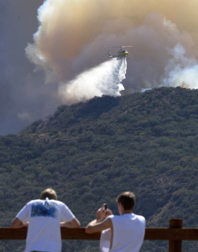 Residents watch a helicopter drop water during a wildfire Thursday in Ventura County, Calif. (Associated Press)