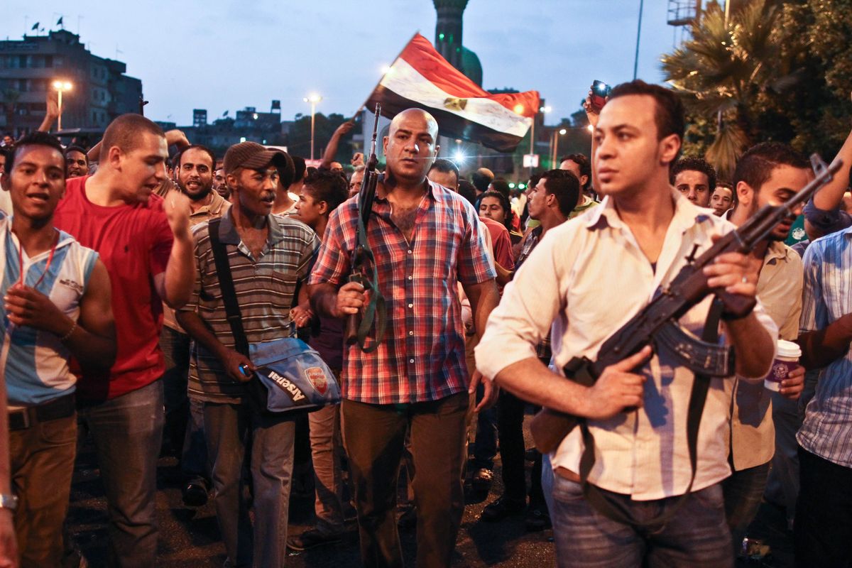 Plainclothes policemen walk with protesters opposed to Egyptian President Mohammed Morsi at the site of clashes with opposing protesters in the Kit Kat neighborhood of Giza, Egypt, on Tuesday. (Associated Press)