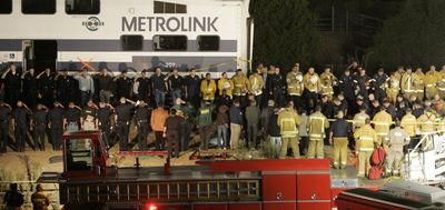 Police, firefighters and others stand as an honor guard as the body of a Los Angeles Police Department officer who was killed in the crash of a Metrolink train is carried from the wreckage in the Chatsworth area of Los Angeles shortly after 10 p.m. Friday.  (Associated Press / The Spokesman-Review)