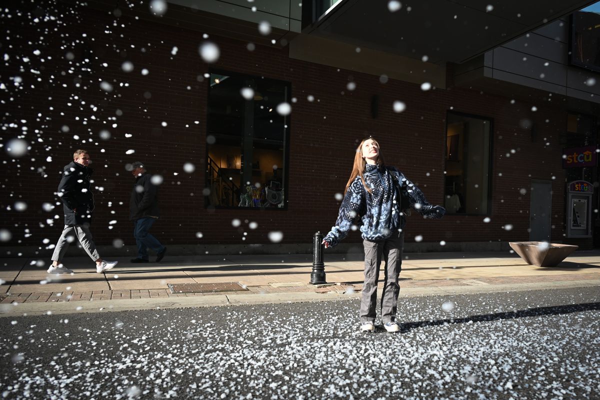 Fiona Whitver, of Spokane, stands in a flurry of fake snowflakes Tuesday on Wall Street in downtown Spokane as machines blow a blanket of soapy bubbles from overhead.  (Jesse Tinsley/THE SPOKESMAN-REVIEW)