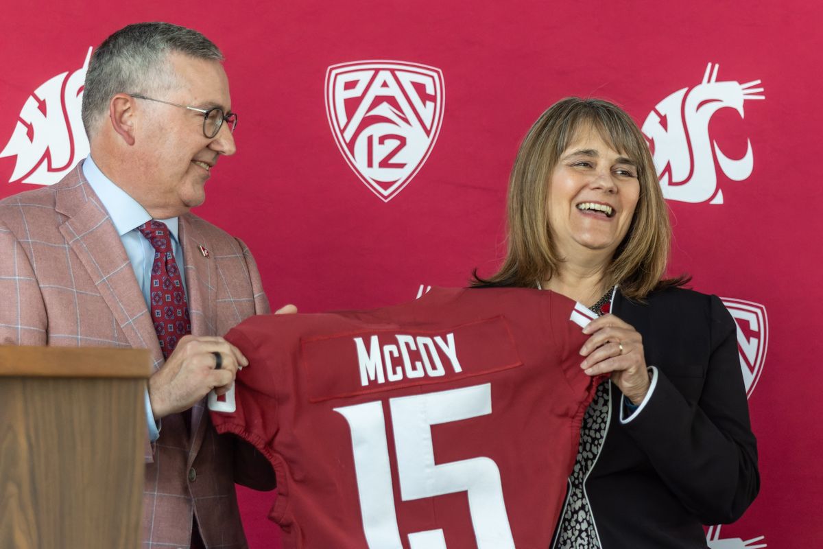 Anne McCoy holds up a jersey with her name on it with Washington State University President Kirk Schulz after she was introduced as the university