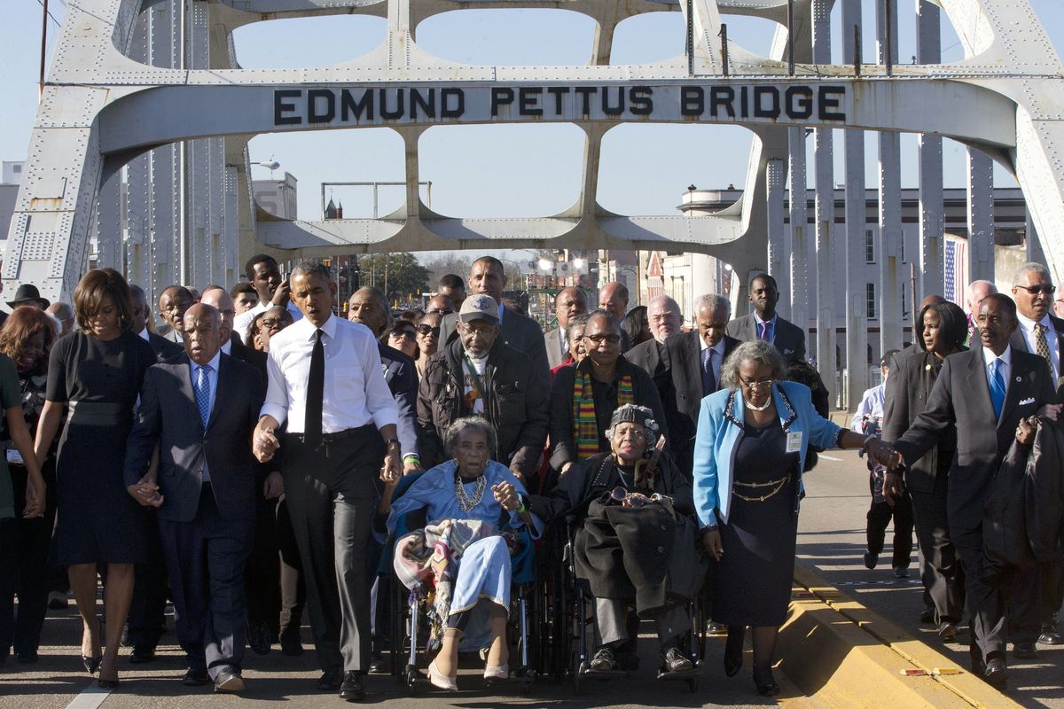 In this March 7, 2015, photo, singing “We Shall Overcome,” President Barack Obama, third from left, walks holding hands with Amelia Boynton, who was beaten during “Bloody Sunday” in 1965, as they and the first family and others, including Rep. John Lewis, D-Ga, to Obama’s left,  (Jacquelyn Martin)