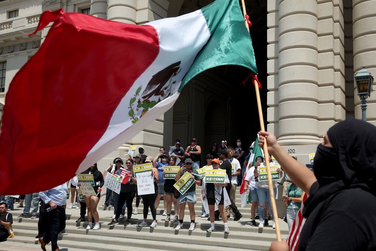 A man waves a Mexican flag during a protest Thursday in front of City Hall in Los Angeles City. (Jason Armond/Los Angeles Times/TNS)