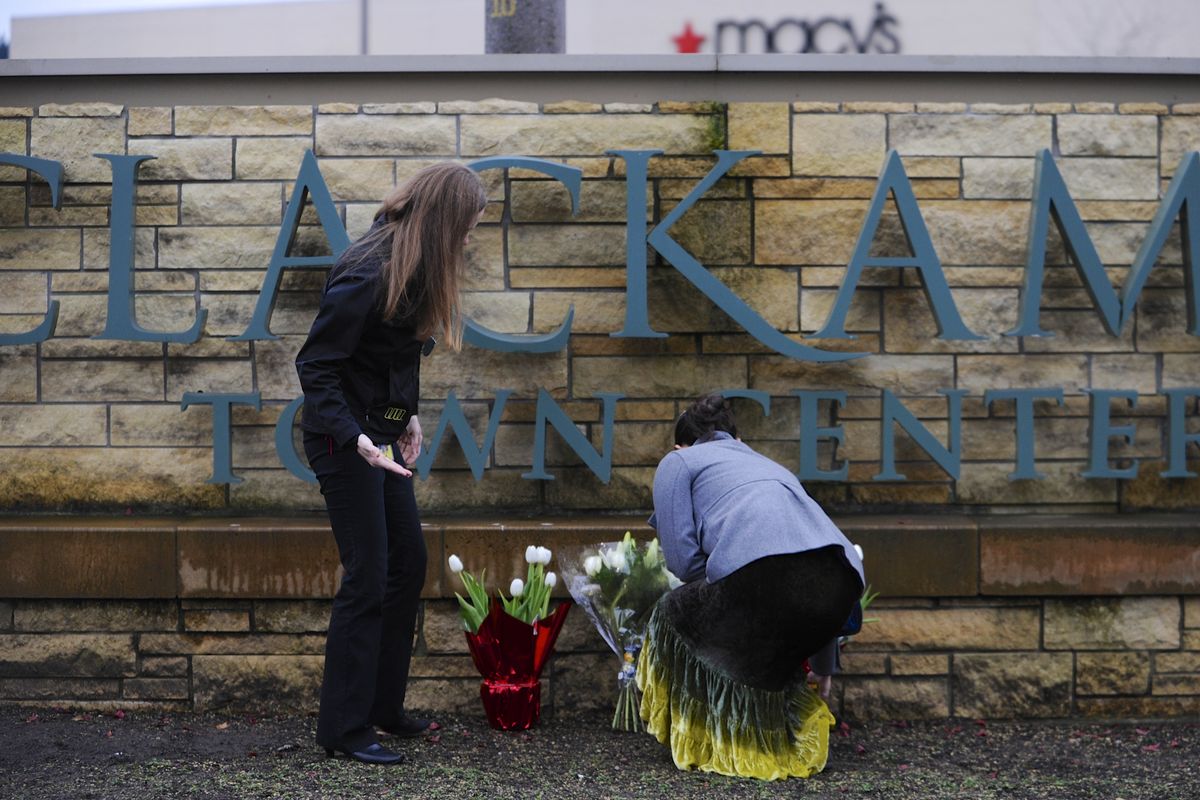 Leslie King, right, and Tenille Beseda place flowers Wednesday at the entrance to the scene of a multiple shooting at Clackamas Town Center Mall in Portland. (Associated Press)