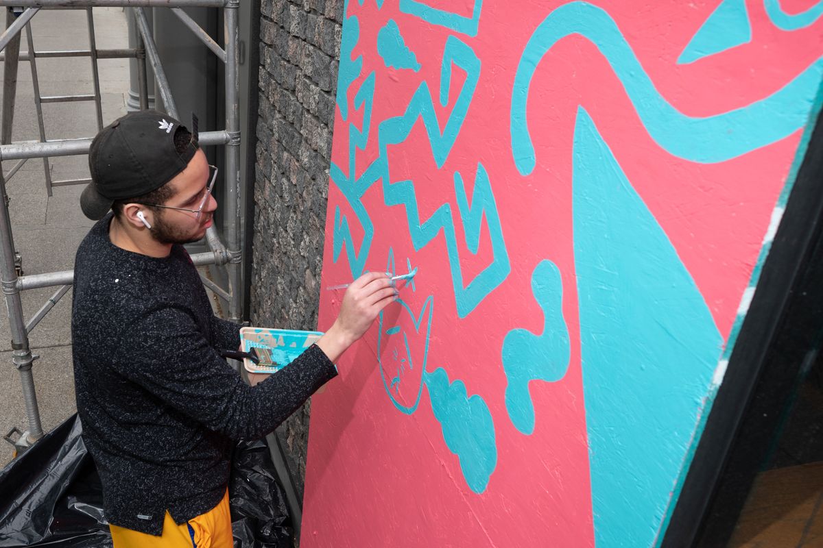 Graphic Artist Joshua Thomas paints a mural of whimsical characters on a boarded up window at the Empire State Building on West Riverside Avenue, Sat., June 6, 2020.  (COLIN MULVANY/The Spokesman-Review)