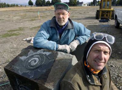 
Randy Raak, left, and Dale Young  have been commissioned by Greenstone Corp. to produce art for the new River District neighborhood in Liberty Lake. They are grinding shapes such as the sun into basalt rocks.
 (Photos by DAN PELLE / The Spokesman-Review)