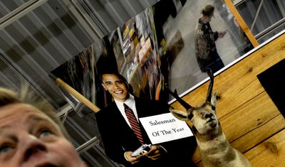 Nathaniel Pulliam of Black Sheep Sporting Goods works the gun counter on Wednesday. The owners put up the cutout of Barack Obama after the election.  (Kathy Plonka / The Spokesman-Review)