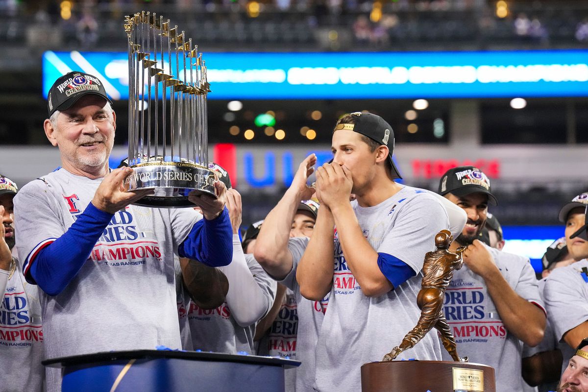 Texas Rangers manager Bruce Bochy holds the Commissioner’s Trophy to the cheers of shortstop Corey Seager after winning the World Series with a 5-0 victory over the the Arizona Diamondbacks in Game 5 on Nov. 1, 2023, in Phoenix. (Smiley N. Pool)