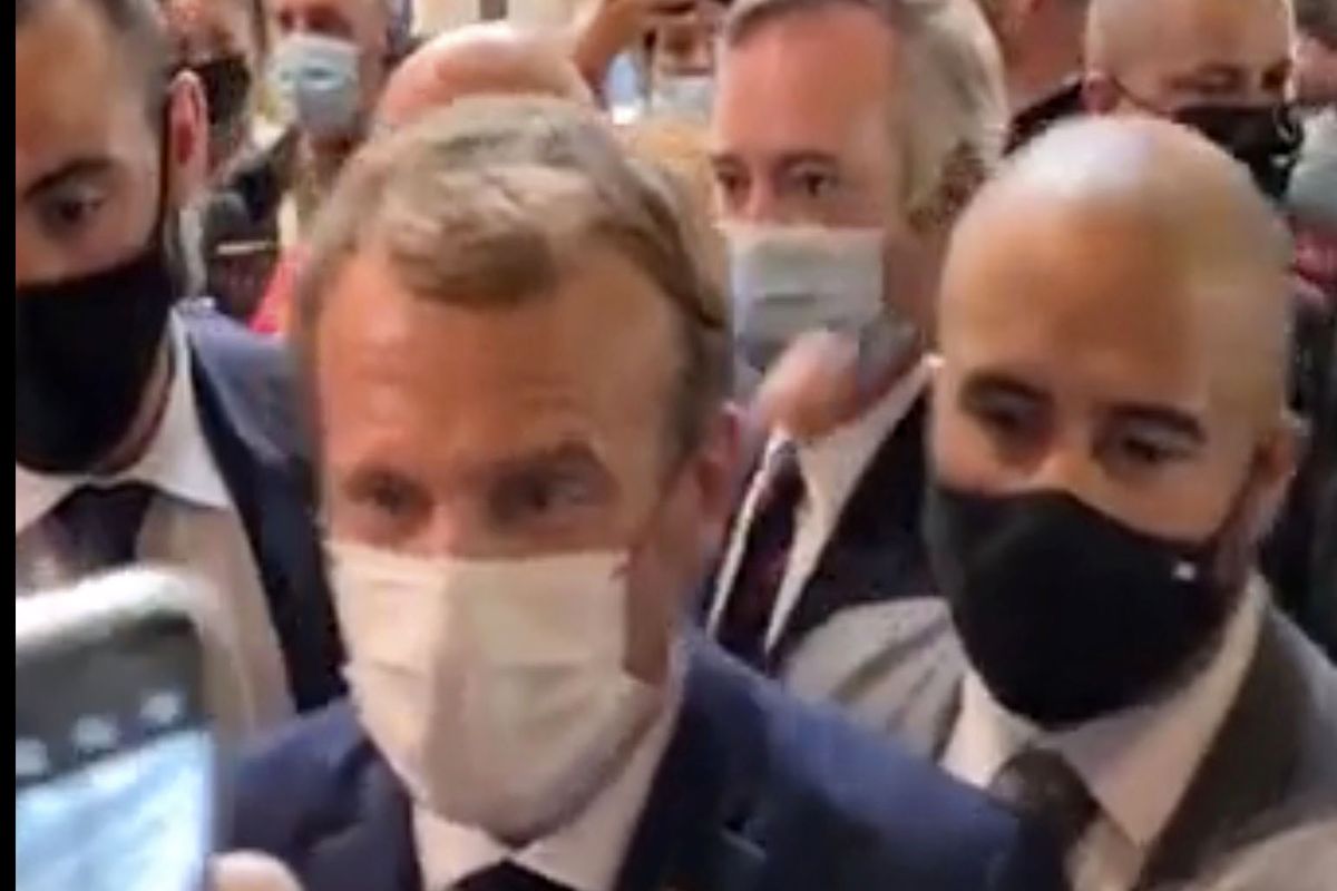 This image from video made available by Lyonmag.com shows an egg thrown toward French President Emmanuel Macron, left, to hit him on the shoulder as he walks through the restaurant trade fair in Lyon, France, Monday Sept. 27, 2021. Macron was visiting the International Catering, Hotel and Food Trade Fair to promote French gastronomy.  (UGC)