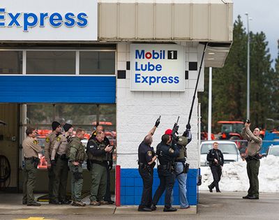 Officers from the Coeur d'Alene Police Department, Kootenai County Sheriff's Office and Idaho State Patrol surround a corner of the Mobil 1 Lube Express on Appleway Avenue while using a camera to check inside a crawl space for suspect who fled police Wednesday in Coeur d'Alene. (Shawn Gust/press)