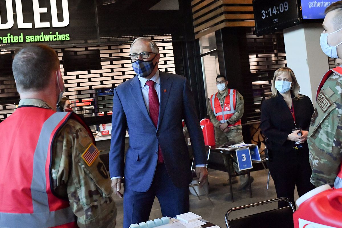 Washington Gov. Jay Inslee speaks with members of the Washington Air National Guard and Washington National Guard on Friday as he tours a mass Covid-19 vaccination site at Spokane Arena.  (Tyler Tjomsland/The Spokesman-Review)