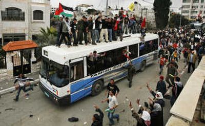 
Released Palestinian prisoners wave from atop a bus as they arrive at Palestinian President Mahmoud Abbas' headquarters in the West Bank after their release from an Israeli jail on Monday. Associated Press
 (Associated Press / The Spokesman-Review)
