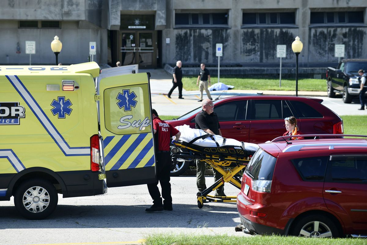 Medical personnel load the body of one victim as a second deceased victim awaits following following a shooting near the Kankakee County Courthouse, Thursday morning, Aug. 26, 2021, in Kankakee, Ill. Two people were killed and another was injured Thursday morning, Mayor Christopher Curtis said.  (Tiffany Blanchette)