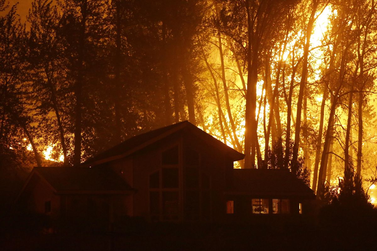 A wildfire burns behind a home on Twisp River Road, Thursday, Aug. 20, 2015 in Twisp, Wash. (Ted S. Warren / AP)
