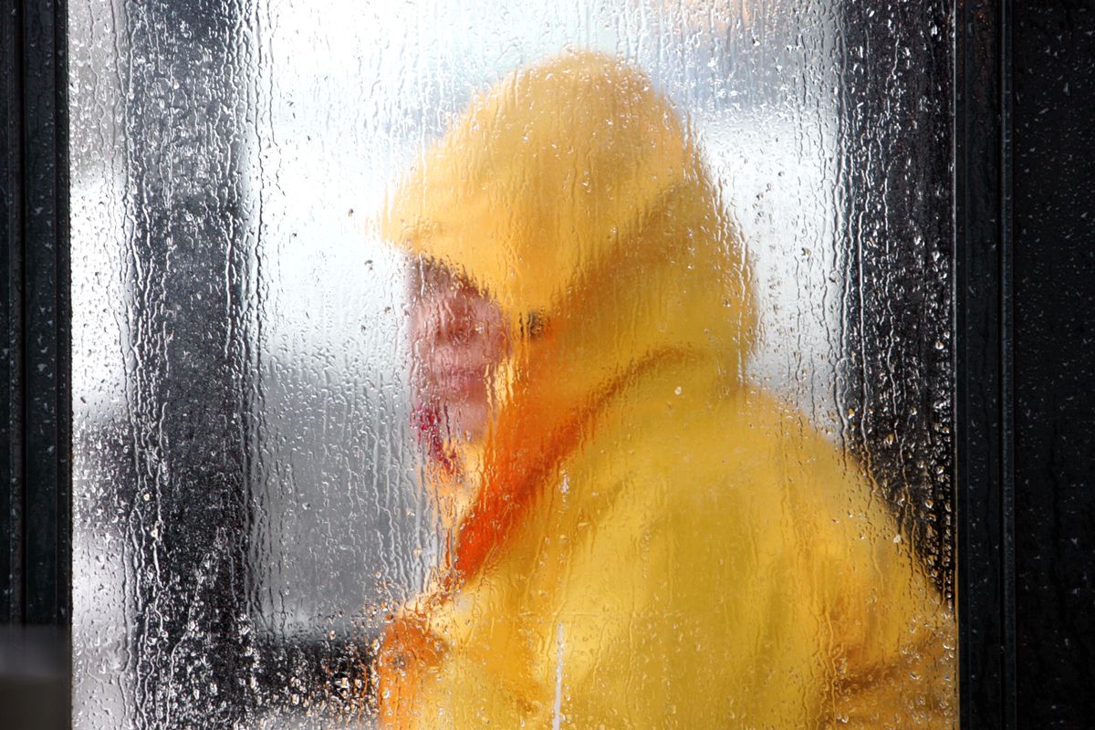 Rain drops collect on a a bus stop wall as Lori Dietrich waits for the bus on in Tacoma on Tuesday, Jan. 6, 2009. (Associated Press)