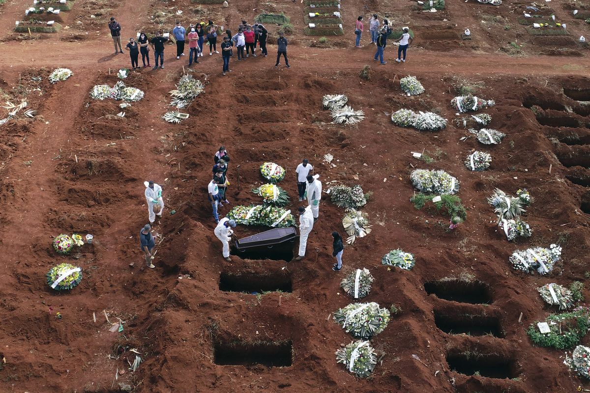 In this April 7, 2021, photo, cemetery workers wearing protective gear lower the coffin of a person who died from complications related to COVID-19 into a gravesite at the Vila Formosa cemetery in Sao Paulo, Brazil. Nations around the world set new records Thursday, April 8, for COVID-19 deaths and new coronavirus infections, and the disease surged even in some countries that have kept the virus in check. Brazil became just the third country, after the U.S. and Peru, to report a 24-hour tally of COVID-19 deaths exceeding 4,000.  (Andre Penner)
