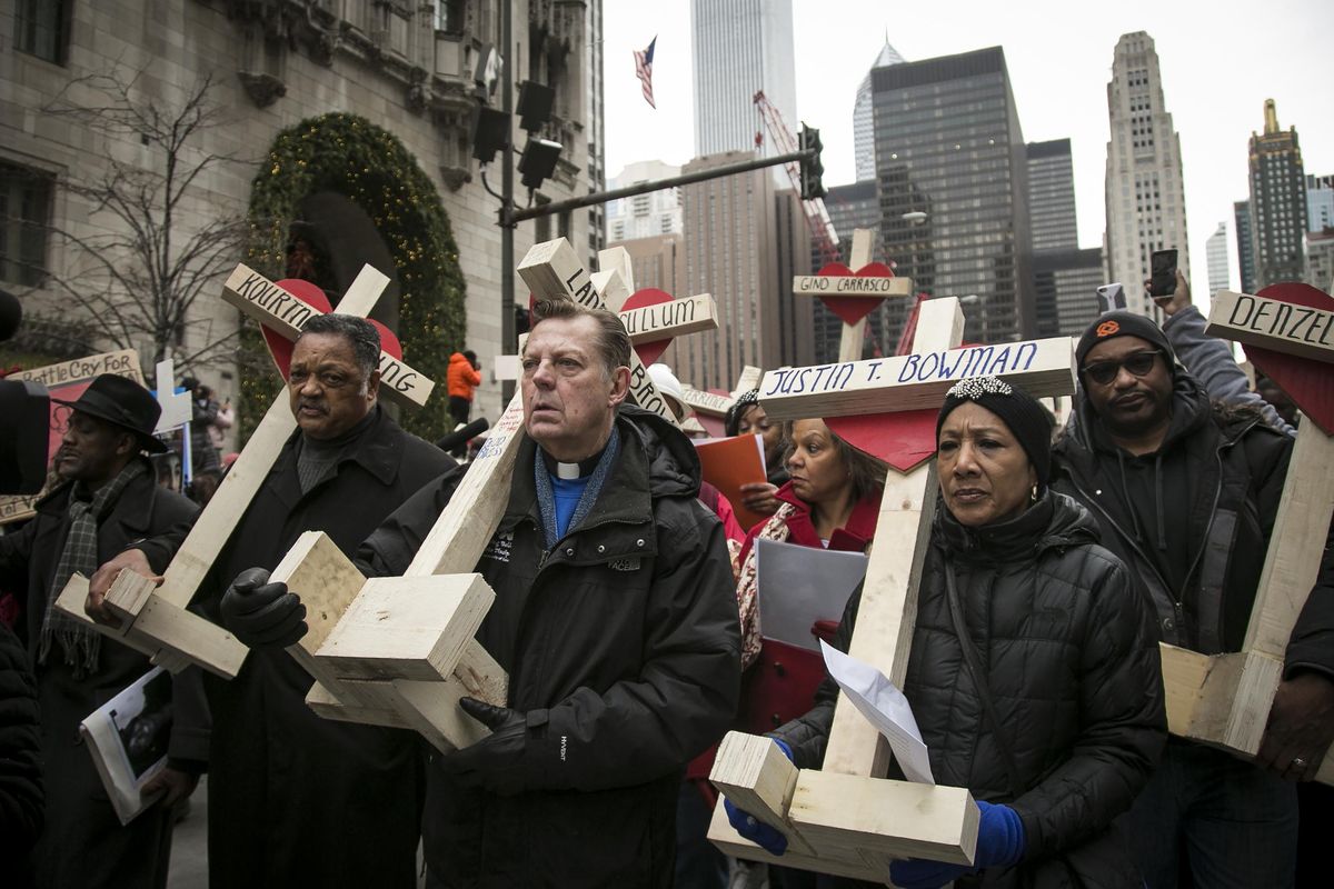 The Rev. Michael Pfleger, third from left, the Rev. Jesse Jackson, second from left, and state Sen. Jacqueline Collins, right, lead hundreds in a march down Michigan Avenue, carrying crosses for all those killed by Chicago violence in 2016 Saturday, Dec. 31, 2016, in Chicago. (Ashlee Rezin / Chicago Sun-Times)