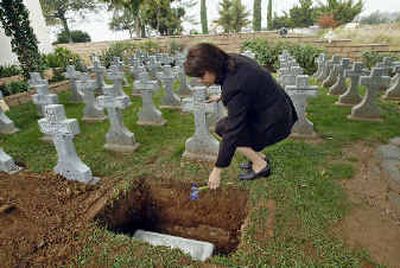 
Debi Faris-Cifelli, founder and director of Garden of Angels, tosses a flower in the grave of baby Melissa, an abandoned newborn in November. 
 (Associated Press / The Spokesman-Review)