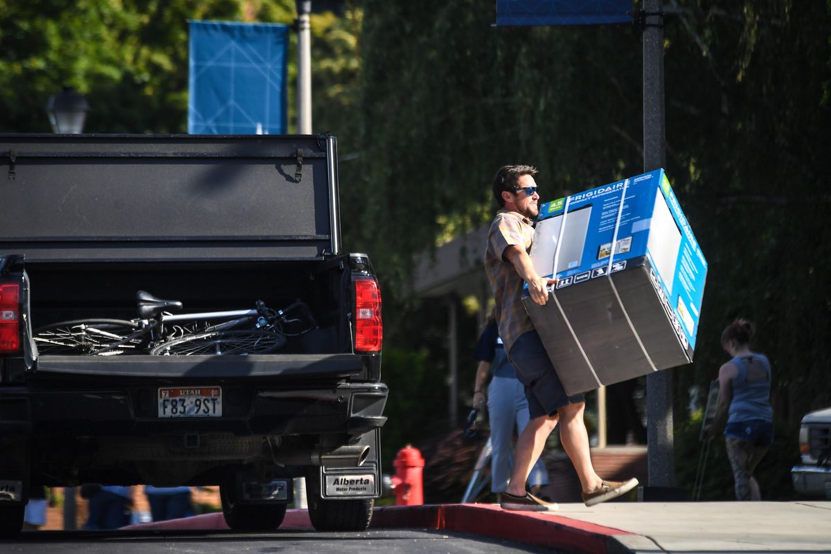 Jacob Sims, of Herriman, Ut., packs a mini-fridge up to a dorm room in Catherine-Monica Hall for his son Micah on the first day of freshman move-in at Gonzaga University, Friday, Aug. 23, 2019. (Dan Pelle / The Spokesman-Review)