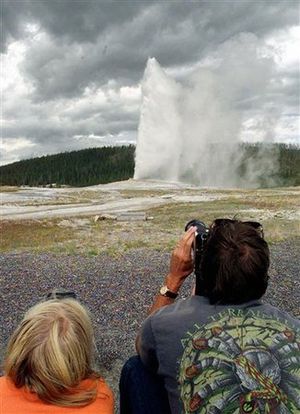 An unidentified pair of visitors to the Yellowstone National Park photograph the Old Faithful geyser as it rockets 100-feet skyward , in Wyoming. Hundreds of small earthquakes at Yellowstone National Park in recent weeks have been an unsettling reminder for some people that underneath the park's famous geysers and majestic scenery lurks one of the world's biggest volcanoes. (AP Photo/Kevork Djansezian)
 (Kevork Djansezian / The Spokesman-Review)