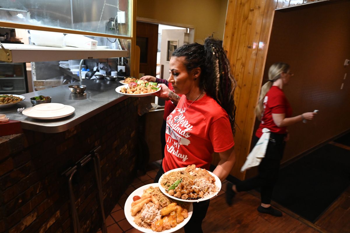 China Dragon bar manager Mandie Dever loads her arms with plates of food destined for customers in the bar area at the restaurant’s kitchen window during the dinner rush Sunday at the north Spokane restaurant.  (Jesse Tinsley/THE SPOKESMAN-REVIEW)