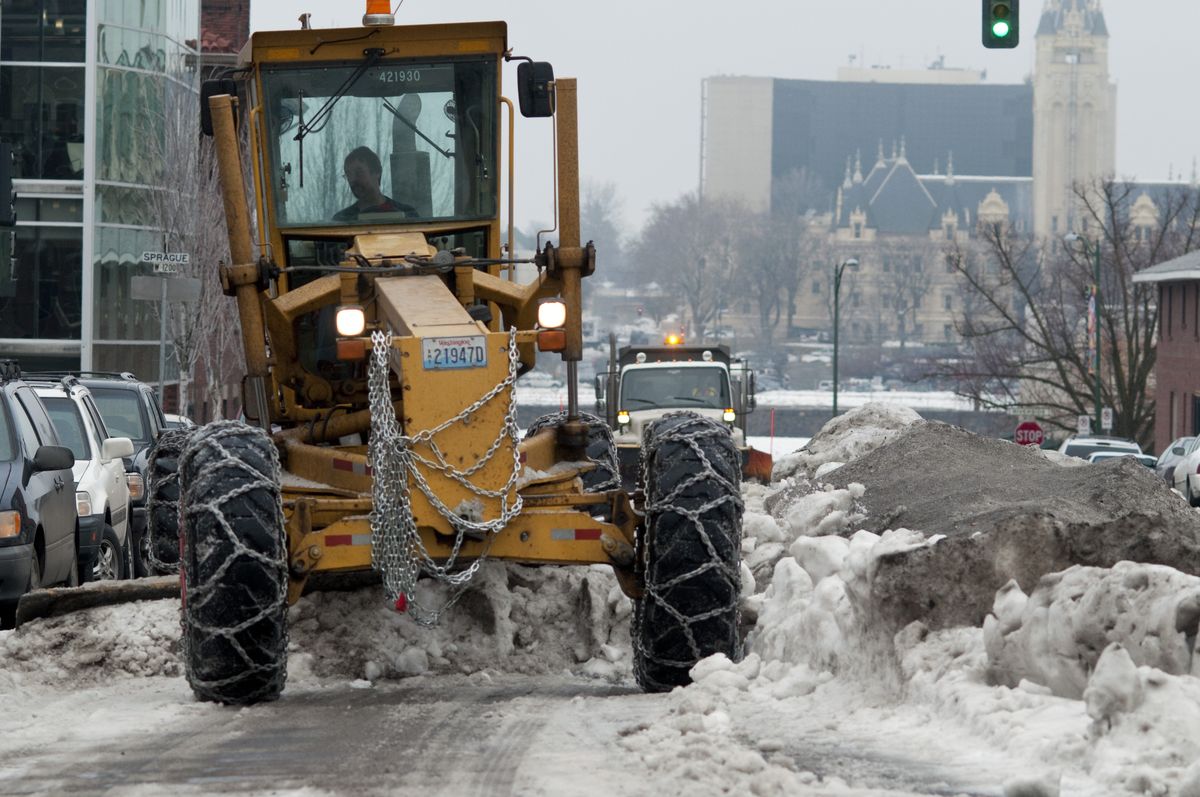 City workers tackle a berm Wednesday on Jefferson Street between Riverside and Sprague avenues.  Spokane is considering buying  more plows to install on city vehicles. (Colin Mulvany / The Spokesman-Review)