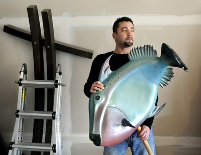 Michael Larsen has been an industrial sculptor for the past 13 years. He holds his triggerfish creation made from fiberglass and foam core.  (Dan Pelle)