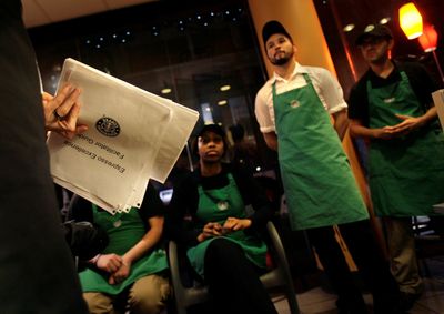 In this February photo, Starbucks employees listen to their manager during a training session at a store in New York. In a letter to employees Tuesday announcing the newest wave of job cuts, Chief Executive Howard Schultz said about 70 percent of employees in stores set to be closed this month have been transferred to other locations.  (Associated Press / The Spokesman-Review)