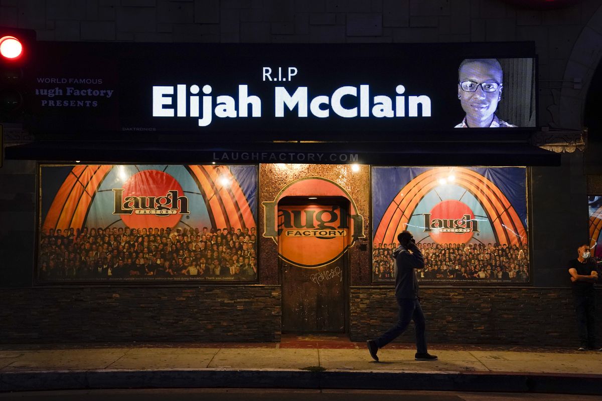 FILE - In this Aug. 24, 2020, file photo, a man walks past a display showing an image of Elijah McClain outside Laugh Factory during a candlelight vigil for McClain in Los Angeles. Colorado’s attorney general said Wednesday, Sept. 1, 2021 that a grand jury indicted three officers and two paramedics in the death of Elijah McClain, a Black man who was put in a chokehold and injected with a powerful sedative two years ago in suburban Denver.  (Jae C. Hong)