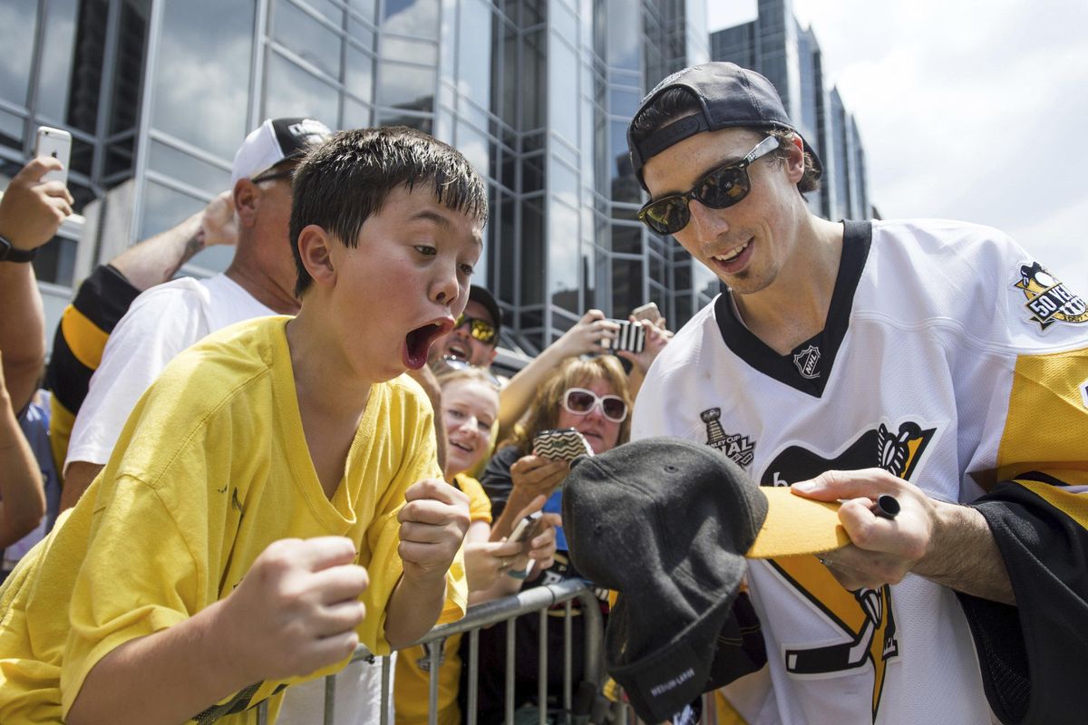 Pittsburgh Penguins’ Marc-Andre Fleury signs a hat for a young fan during the team’s Stanley Cup NHL hockey victory parade on Wednesday, June 14, 2017, in Pittsburgh. (Steph Chambers / Pittsburgh Post-Gazette via AP)