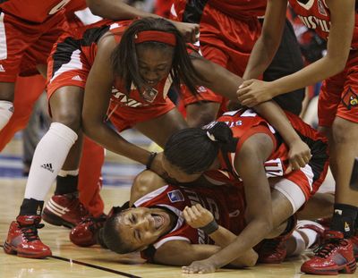 Angel McCoughtry, bottom, is mobbed by her Louisville teammates after beating Oklahoma for a berth in the national title game. (Associated Press / The Spokesman-Review)