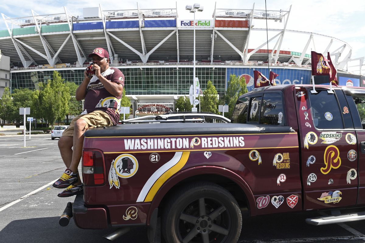 Rodney Johnson sits on the back of a truck decorated with Washington Redskins decals outside FedEx Field in Landover, Md., on  (Associated Press)