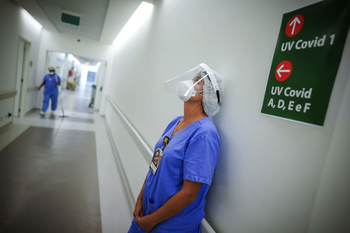 In this March 19, 2021 photo, a health worker pauses in the ICU unit for COVID-19 patients at the Hospital das Clinicas in Porto Alegre, Brazil. As Brazil hurtles toward an official COVID-19 death toll of 500,000 — second-highest in the world — science is on trial inside the country and the truth is up for grabs.  (Jefferson Bernardes)