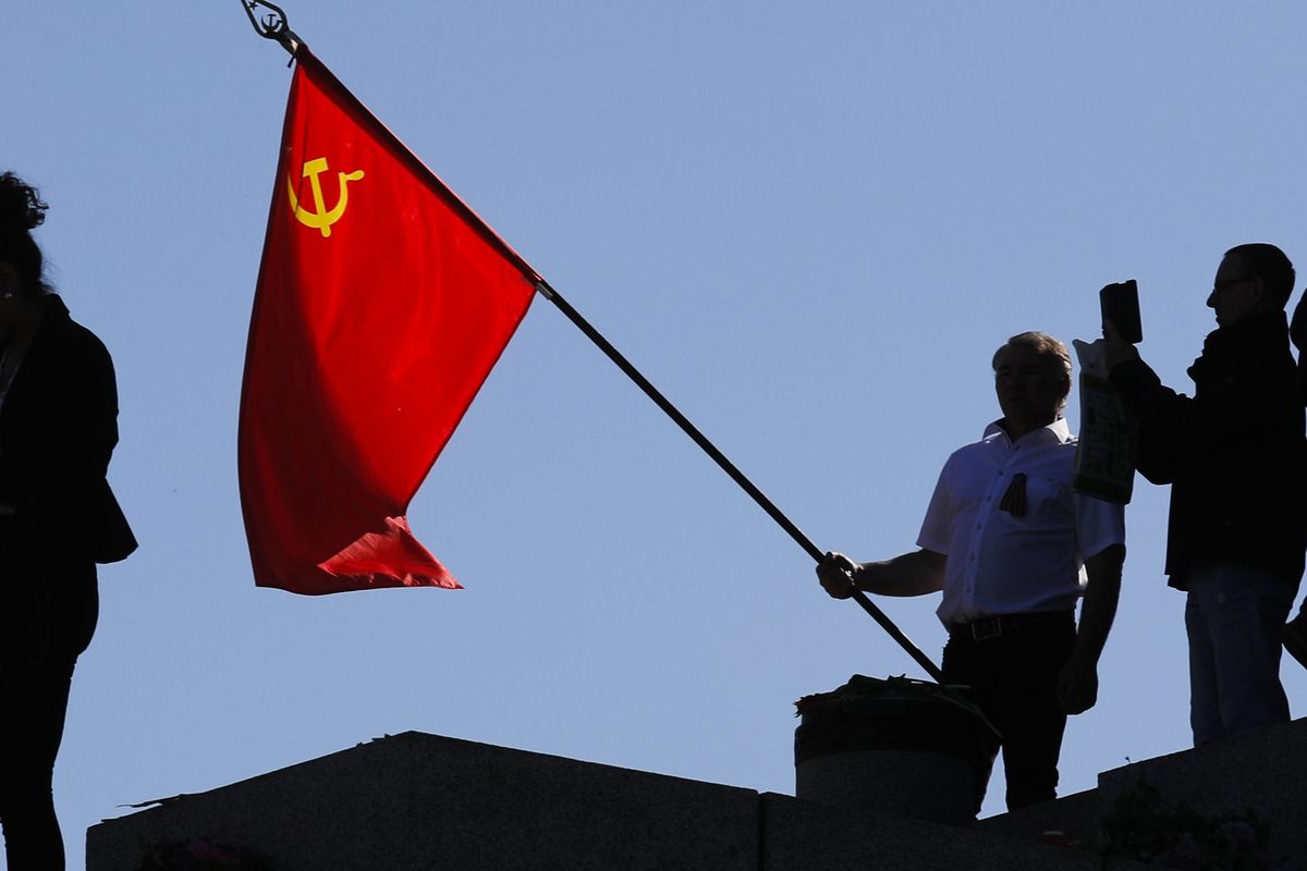 FILE - In this file photo dated Saturday, May 9, 2020, a man holds a Soviet flag during a ceremony at the Soviet War memorial to mark the 75th anniversary of Victory Day at the district Treptow in Berlin, Germany. An influential committee of British lawmakers plans to publish its findings Tuesday July 21, 2020, reporting on Russian interference in British politics, amid criticism the government delayed its release for more than six months to shield Prime Minister Boris Johnson and his Conservative Party from embarrassment.  (Markus Schreiber)