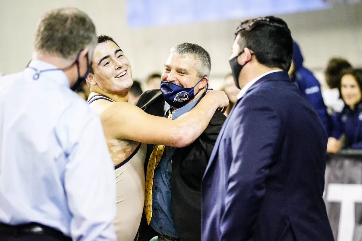Mead’s JT Connors, left, hugs coach Phil McLean after winning the State 3A 220-pound title Feb. 19 in Tacoma.  (Jake Mark Sr/Courtesy)