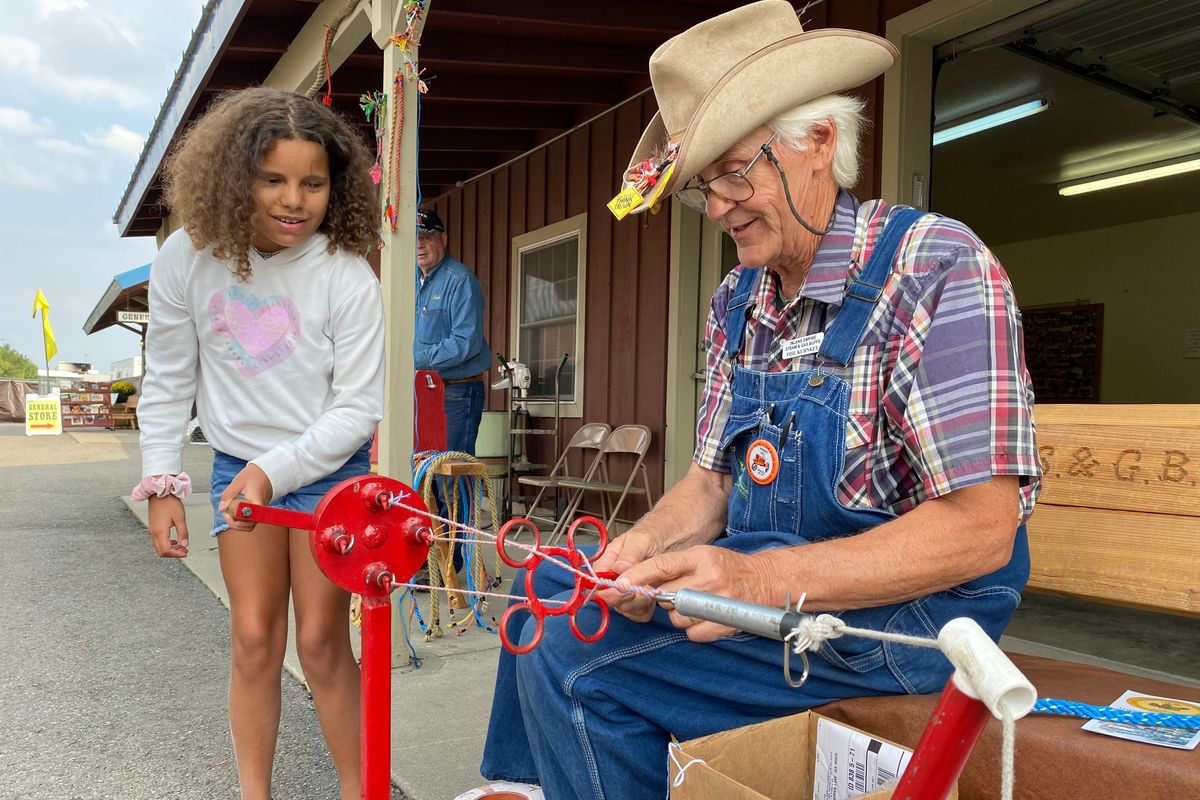 Nevella Parris, 10, spins three strings together to form a colorful rope for herself Wednesday at the Spokane County Interstate Fair, while Phil Kuhnkey guides her through the traditional technique.  (James Hanlon/The Spokesman-Review)