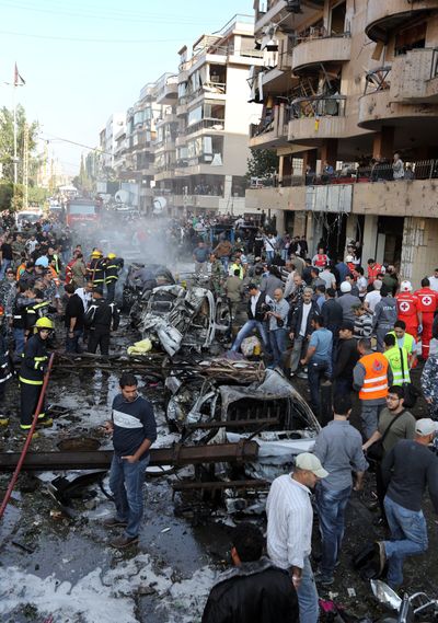 Lebanese people gather at the scene where two explosions struck near the Iranian Embassy killing many, in Beirut, Lebanon, Tuesday. (Associated Press)