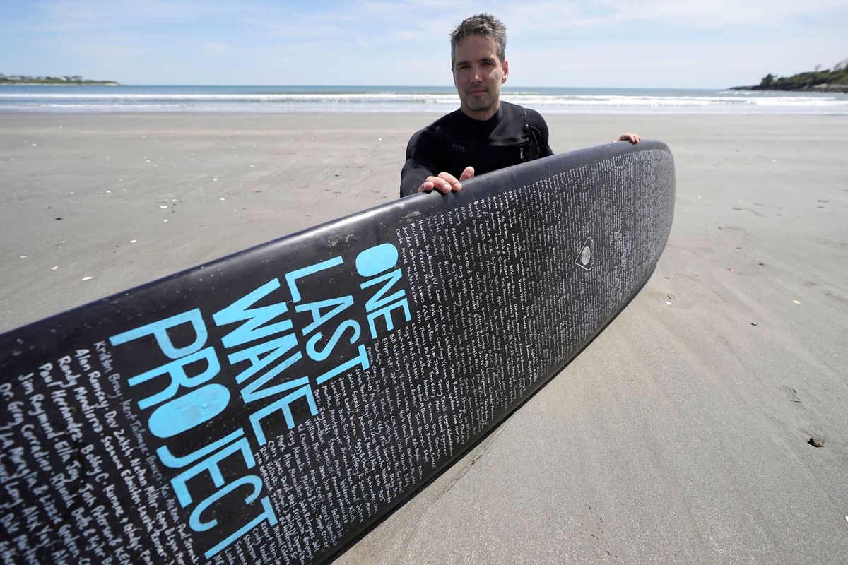 Dan Fischer, of Newport, R.I., sits for a photograph on May 18 with his surfboard on Easton’s Beach in Newport.  (Steven Senne)