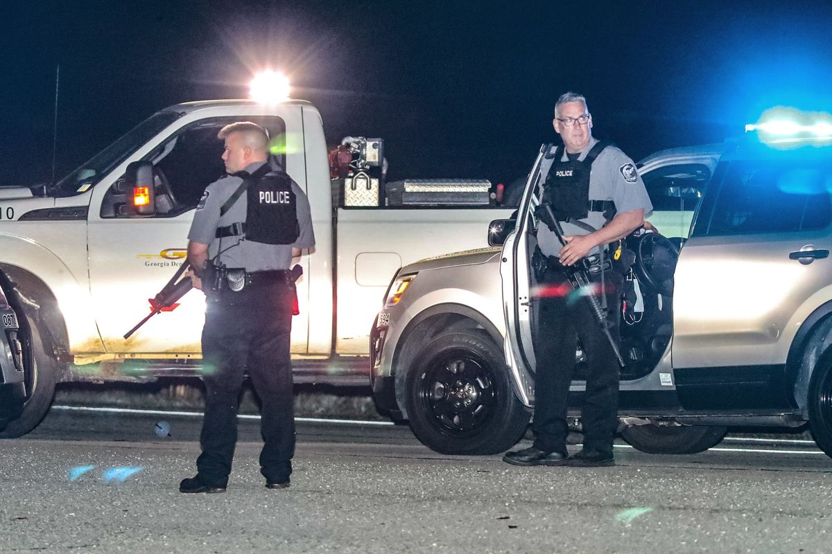 Police officers stand at the scene following a police chase Monday, April 12, 2021, in Carroll County, Ga. Georgia authorities say multiple officers were injured when the passenger of a car shot them during a police chase that ended with one suspect killed and the other arrested.  (John Spink)