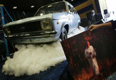 
A Kruse worker hangs photos of Pope John Paul II around a 1975 Ford Escort GL owned by the late pontiff. 
 (Associated Press / The Spokesman-Review)