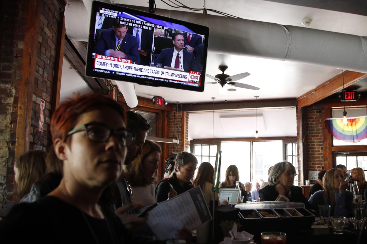 People watch live television broadcast of former FBI director James Comey testifying before the Senate Select Committee on Intelligence, on Capitol Hill, with a group of other people at Shaw’s Tavern in Washington, Thursday, June 8, 2017. (Manuel Balce Ceneta / Associated Press)