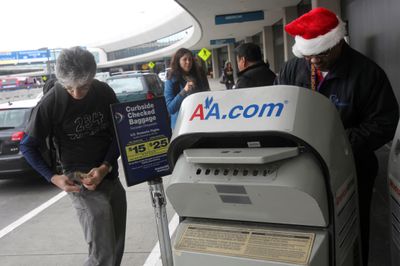 Arman Garakani gets money out to pay baggage fees to a skycap at the American Airlines bag drop at San Francisco International Airport in San Francisco on Tuesday.  (Associated Press / The Spokesman-Review)