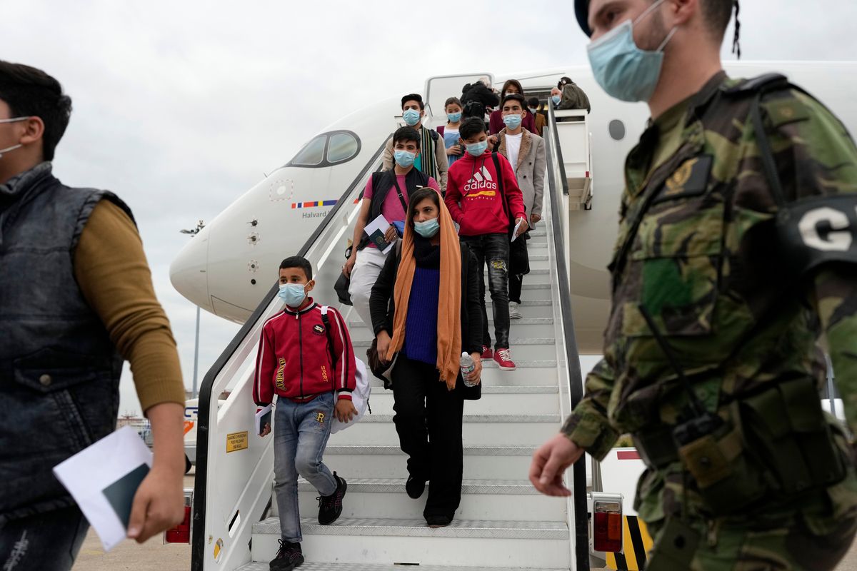 Afghan music students, faculty members and their families disembark from an airplane at Lisbon military airport, Monday, Dec. 13, 2021. A group of 273 students, faculty members and their families from the Afghanistan National Institute of Music arrived Monday in Portugal, where they are being granted asylum and where they hope to rebuild their acclaimed school.  (Armando Franca/Associated Press)