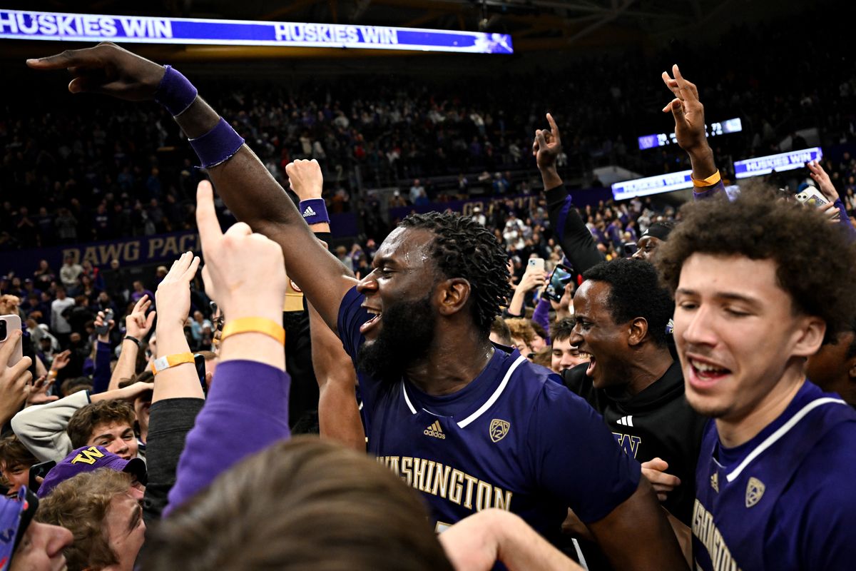 Washington Huskies center Franck Kepnang (11) celebrates with fans who rushed the floor after Washington defeated the Gonzaga Bulldogs during the second half of a college basketball game on Saturday, Dec. 9, 2023, at Alaska Airlines Arena at Hec Edmundson Pavilion in Seattle, Wash. Washington won the game 78-73.  (Tyler Tjomsland/The Spokesman-Review)