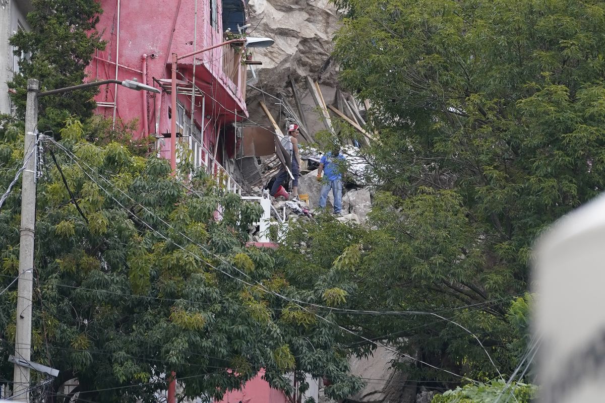 Firefighters scale a three-story pile of rocks in Tlalnepantla, on the outskirts of Mexico City, when a mountain gave way on Friday, Sept. 10, 2021, plunging rocks the size of small homes onto a densely populated neighborhood.  (Eduardo Verdugo)