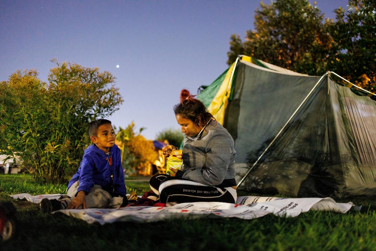 Frangeny Mendoza, 27, and her son Ediomar Mendoza, 8, both from Venezuela, eat chips before sleeping in a park across the street from the 22nd District police station on Tuesday in Chicago.  (Armando L. Sanchez/Chicago Tribune/TNS)